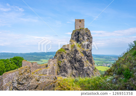 Trosky Castle Ruins stand majestically on a rocky outcrop in Bohemian Paradise, Czechia, surrounded by lush green landscapes and a clear blue sky, offering a glimpse into medieval history. 126931358