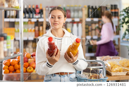 woman chooses juices against the background of buyers 126931481