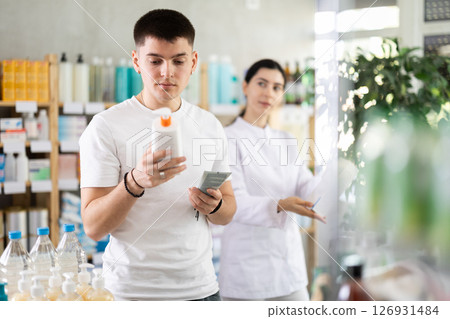 Guy buys emollient cream at pharmacy. Pharmacist offer help and similar product 126931484