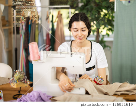 Female seamstress working on sewing machine in workshop 126931619