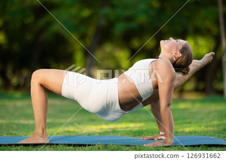 Girl performing Reverse Table Top Pose in summer park 126931662