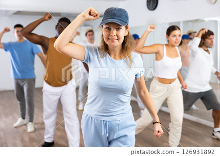 Excited sporty multiracial people practicing new movements steps during dancing training in studio Excited sporty multiracial people practicing new movements steps during dancing training in studio 126931892