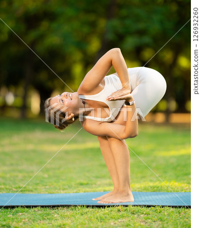 Sporty girl performing yoga asanas on green meadow in summer Sporty girl performing yoga asanas on green meadow in summer 126932260