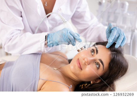 Young brunette undergoing high frequency ultrasound facial treatment 126932269