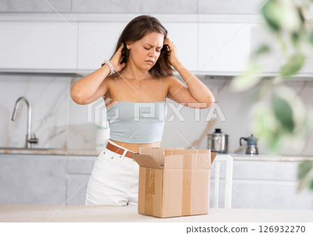 Young upset woman holding open box in kitchen 126932270