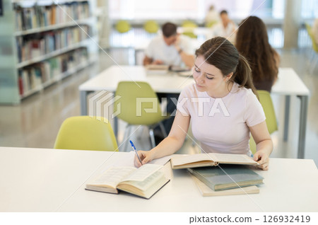 Female student sitting at table and writing 126932419