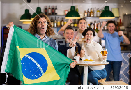 Happy friends of different ages drinking beer and celebrating the victory of the Brazilian team in night bar 126932438