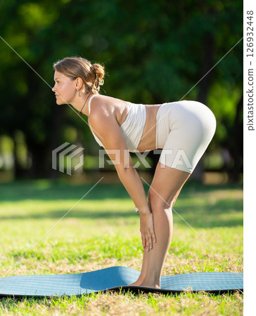 Sporty girl performing yoga asanas on green meadow in summer 126932448