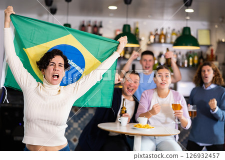 Emotional friends, football fans cheering for favorite Brazil team together while watching match on tv in bar Emotional friends, football fans cheering for favorite Brazil team together while watching match on tv in bar 126932457