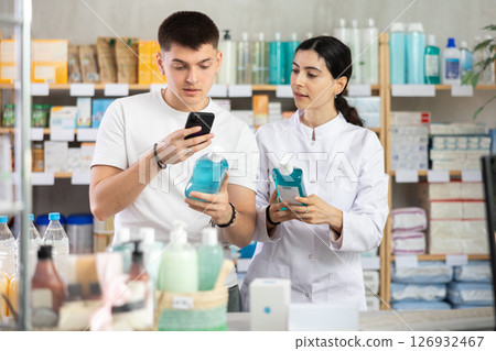 Guy in pharmacy scans QR code mouthwash product. Girl pharmacist offer help and support 126932467