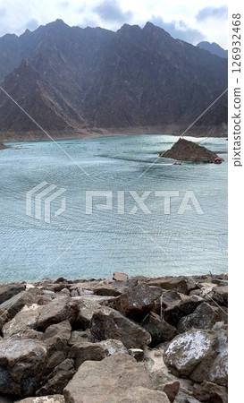 Mountains surround vast water reservoir, tourist destination inviting nature lovers, tourist destination providing panoramic mountains scenery, rocky cliffs enhancing dramatic view. 126932468