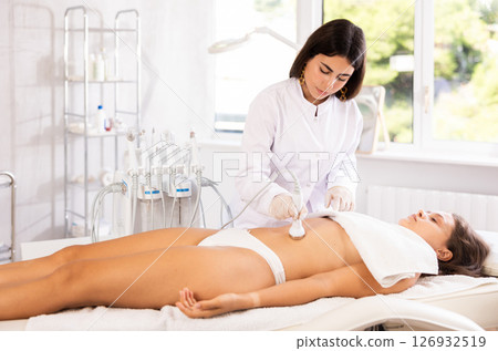 Female doctor making belly beauty massage with vibration attachement Female doctor making belly beauty massage with vibration attachement 126932519