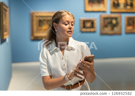 Portrait of young attractive woman holding an information booklet during a visit to fine arts museum Portrait of young attractive woman holding an information booklet during a visit to fine arts museum 126932582