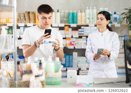 Man scans QR code on box medicated ointment or gel label. Female pharmacist offers to choose right gel Man scans QR code on box medicated ointment or gel label. Female pharmacist offers to choose right gel 126932622