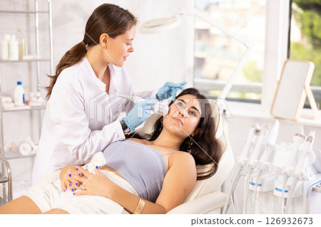Aesthetician administering hardware facial procedure with ice hammer on young woman 126932673