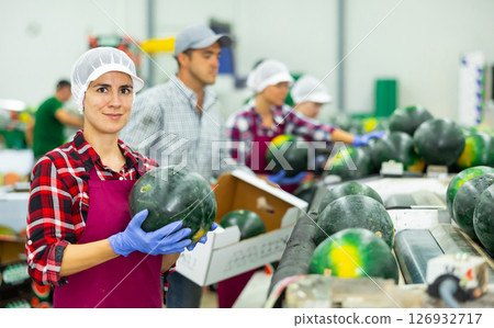 Cheerful Hispanic woman working on watermelons sorting line in fruit warehouse 126932717