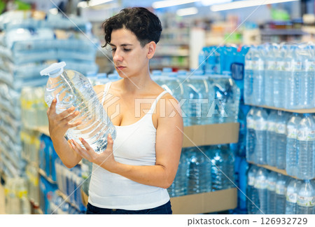 Portrait of adult woman choosing water in bottle at supermarket 126932729