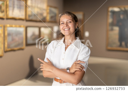 Portrait of young attractive woman holding an information booklet during a visit to fine arts museum Portrait of young attractive woman holding an information booklet during a visit to fine arts museum 126932733
