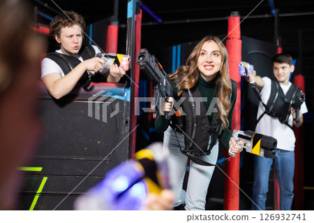 Two guys and one girl running and dodging while playing lasertag 126932741