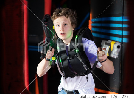 Boy running and dodging while playing lasertag Boy running and dodging while playing lasertag 126932753