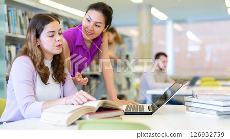 Two woman students, preparing a report on a laptop 126932759