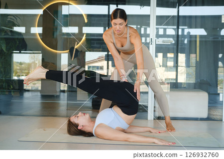 A personal yoga instructor helps the girl do the exercise 126932760