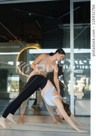 A personal yoga instructor helps the girl do the exercise 126932766