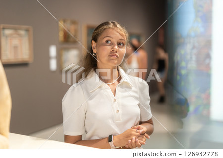 Portrait of young attractive woman holding an information booklet during a visit to fine arts museum 126932778