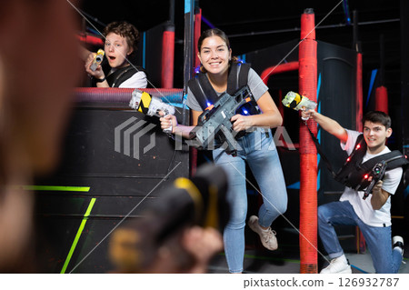 Portrait of excited people playing enthusiastically laser tag game two teams opposite each other in room Portrait of excited people playing enthusiastically laser tag game two teams opposite each other in room 126932787