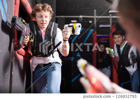 Portrait of positive man with laser gun having fun with her friends on lasertag arena 126932793