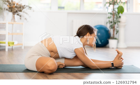 Experienced girl fitness club teacher performs janu shirshasana Experienced girl fitness club teacher performs janu shirshasana 126932794