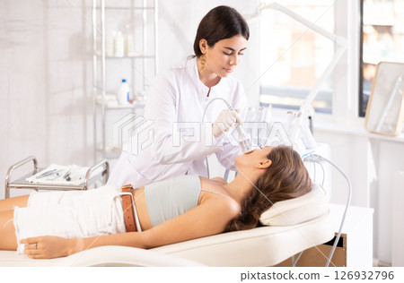 female doctor making facial beauty procedure with ice hummer female doctor making facial beauty procedure with ice hummer 126932796