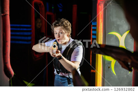 Excited teenager having fun playing lasertag in arena 126932802