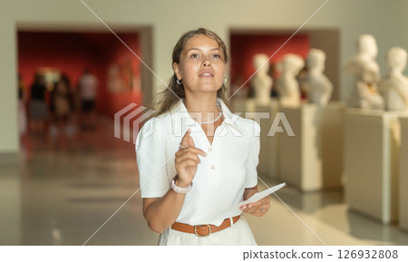 Woman with sheet piece of paper in hands view sculpture in museum hall 126932808