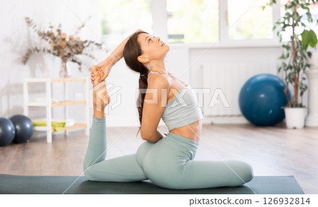 Experienced girl fitness club teacher performs pigeon asana, eka pada rajakapotasana Experienced girl fitness club teacher performs pigeon asana, eka pada rajakapotasana 126932814
