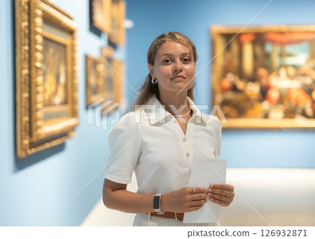 Portrait of young attractive woman holding an information booklet during a visit to fine arts museum 126932871
