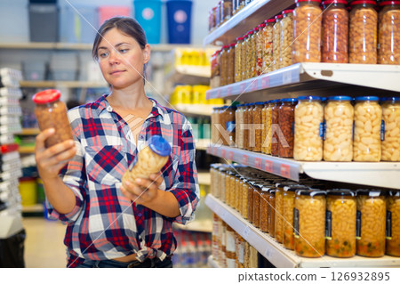 Young woman choosing canned beans in sauce in supermarket 126932895