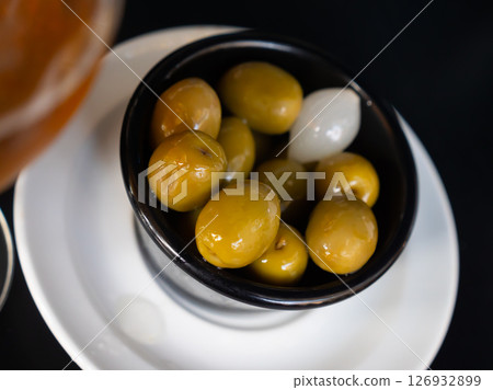 Delicious large green olives with pits served on platter with onions Delicious large green olives with pits served on platter with onions 126932899