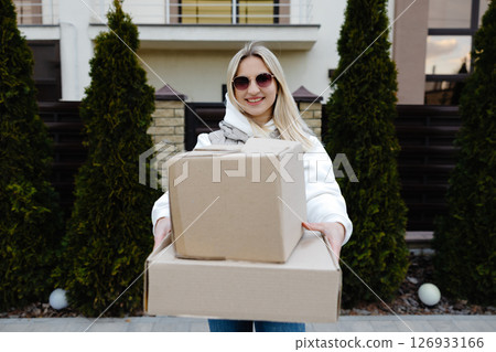 Smiling delivery woman holding a big cardboard box 126933166