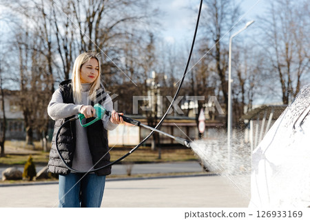 Woman washing her car with high pressure washer at self-service car wash 126933169