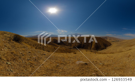 Dry, open landscape with rolling hills under a bright sun. Dry, open landscape with rolling hills under a bright sun. 126933549