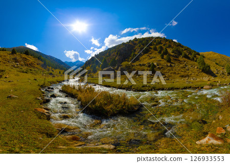 Mountain River Cascading Over Rocks in Sunlit Valley 126933553