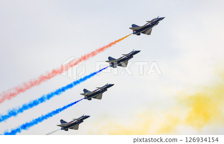 J-10 Acrobatic airshow team from China Air Force on formations with colorful smokes venting from the plane. 126934154