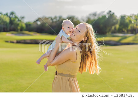 Mother and newborn baby on a meadow in the park. Tender bonding moment in nature. Parenthood, love, and family connection concept 126934183