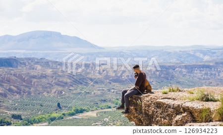 Hiker contemplating gorafe desert landscape from cliff in spain Hiker contemplating gorafe desert landscape from cliff in spain 126934223