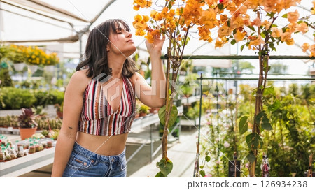 Woman smelling orange bougainvillea flowers in greenhouse 126934238