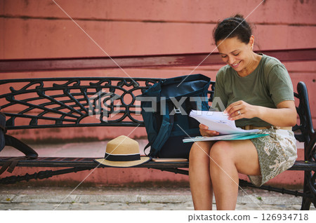 Woman Sitting on a Bench Enjoying Reading Documents Outdoors on a Sunny Day Woman Sitting on a Bench Enjoying Reading Documents Outdoors on a Sunny Day 126934718
