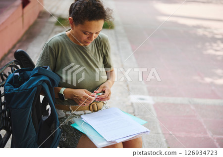 Woman Sorting Documents Outdoors While Preparing for Study or Work Tasks 126934723