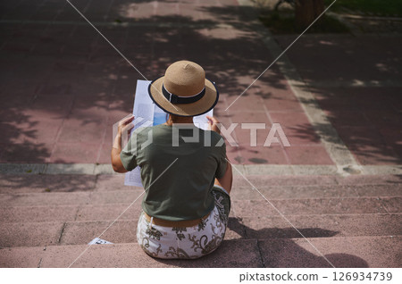 Young Woman Reading Outdoors on Steps Wearing a Straw Hat 126934739