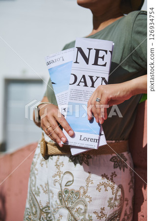 Close-Up of Individual Holding a Folded Paper While Standing Outdoors 126934754